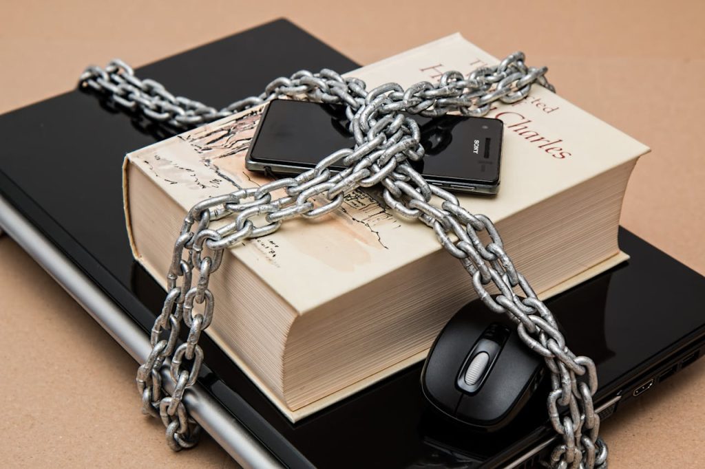 Chain-locked book, phone, and laptop symbolizing digital and intellectual security.